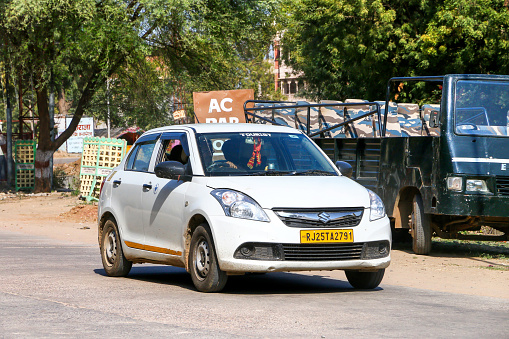 Sawai Madhopur, India - March 1, 2022: White compact car Maruti Suzuki Swift DZire in a city street.