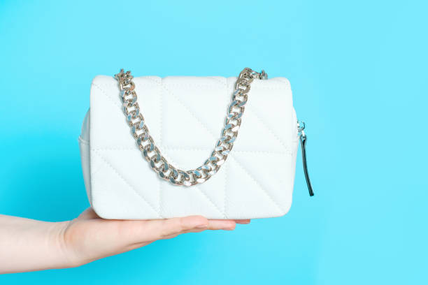 istock Female hand holding a bag with an iron strap on blue background close-up. 1403946976