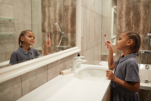 istock Girl Brushing Teeth by Mirror 1403951661