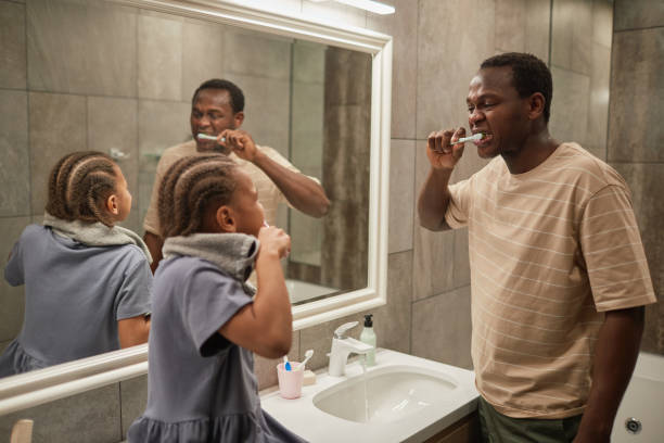 istock Father and Daughter Brushing Teeth 1403951690