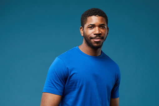 Portrait of smiling black man wearing blue shirt on vibrant blue background and looking at camera, copy space