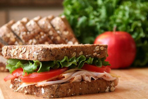 Healthy sandwhich made with whole grain bread, lettuce, tomato, cheese, and roasted chicken slices.