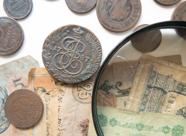 pila de monedas vintage de metal (cobre).  lupa y monedas del imperio ruso en el fondo - brass eagle fotografías e imágenes de stock