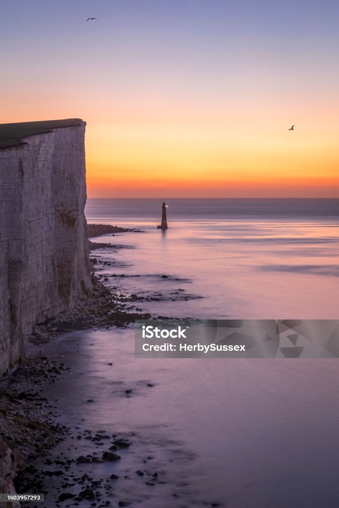 Beachy Head Lighthouse Dawn Calm January morning dawn from the cliff edge of Beachy head looking down at the lighthouse during high tide on the south downs, east Sussex, south east England Tide Stock Photo