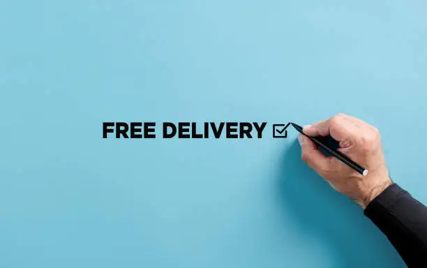 Photo of Male hand puts a tick on the free delivery option. Free delivery or shipping business