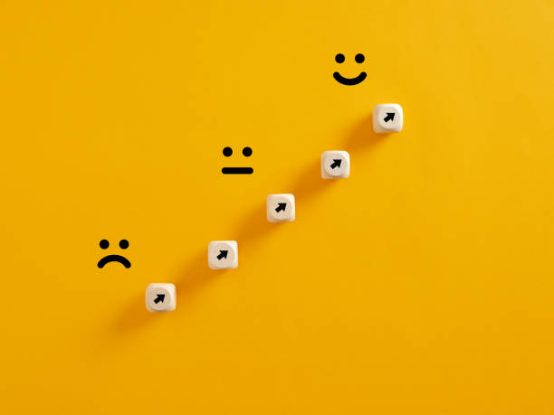 istock Arrows on wooden cubes pointing from a sad expression towards a happy one. Personal growth and aspiration 1403959287