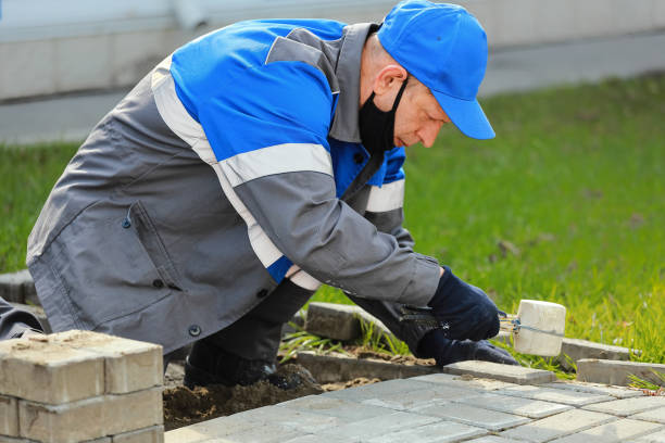 istock Bricklayer lays paving slabs outside. Working man performs landscaping. Builder lays out sidewalk with stone blocks. 1403959867