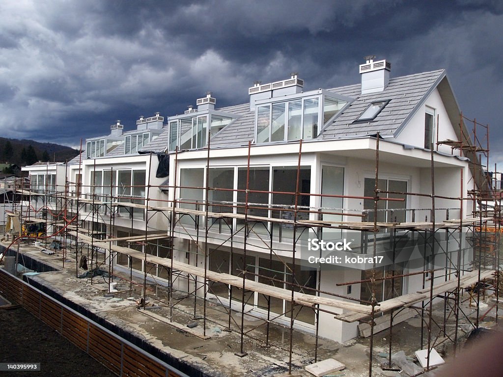 Residential building unfinished 2 Residential building final works on facade, scaffold, modern architecture, wooden fence, heavy clouds Construction Site Stock Photo