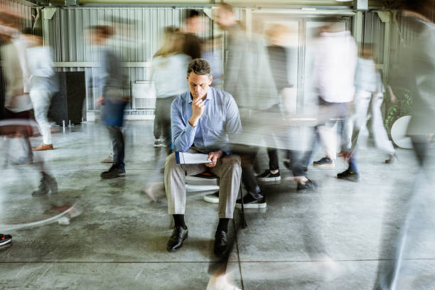 istock Pensive businessman reading reports surrounded by his colleagues in blurred motion. 1403960750