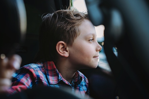 Handsome caucasian boy enjoy travelling by car sitting in child seat Recreation concept. Image with selective focus