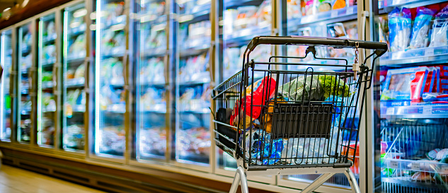 A shopping cart with grocery products in a supermarket