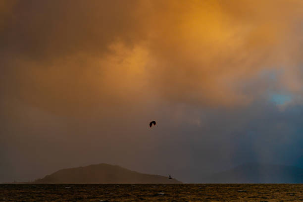 A silhouetted kiteboarder at sunset kiting near the Mokoia Island on Lake Rotorua.