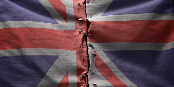 A conceptual image of two halves of a flag of Great Britain connected together along the centre by safety pins.