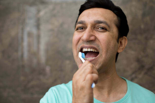 Man brushing his teeth in bathroom Man with toothbrush cleaning his teeth in domestic bathroom at home Oral Health  stock pictures, royalty-free photos & images