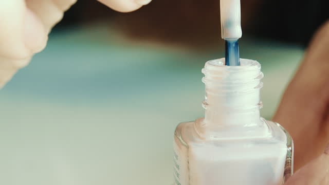 Girl opens a jar of nail polish.
