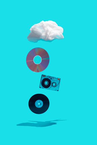 Evolution of music media storage concept. Vinyl record, cassette, CD and storage cloud isolated on bright blue background.