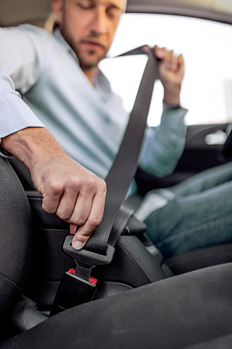 Young man fastening seatbelt in a car