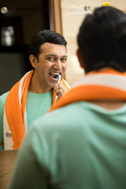 Man with toothbrush cleaning his teeth in domestic bathroom at home