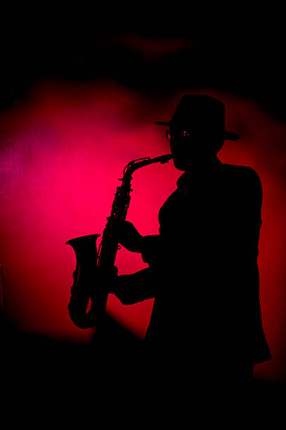 istock Silhouette of jazz man playing saxophone on red background 140396901
