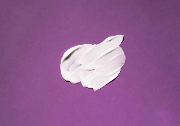 Photo of Swatch of a white cosmetic product on a purple background