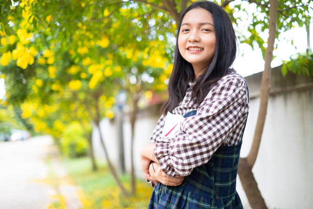 istock A young girl holds a book and standing under a beautiful tree. 1403969480