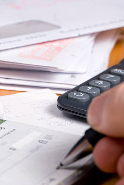 A close-up of a man writing a check to pay the bills stock photo
