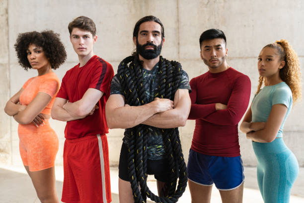 group of young athletes looking at the camera with a serious face, while holding a training rope, multiracial group, focus on bearded man.