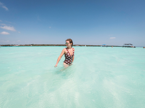 Caucasian woman standing in crystal clear water, exploring Bacalar lake on a hot summer day.