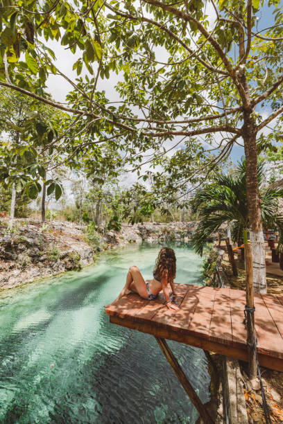 mulher sentada em uma doca em cenote - cancun - fotografias e filmes do acervo