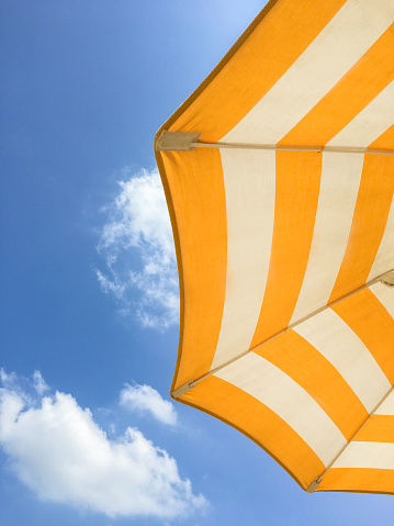 Yellow beach umbrella on a sunny day. Bright colored umbrella on the beach.