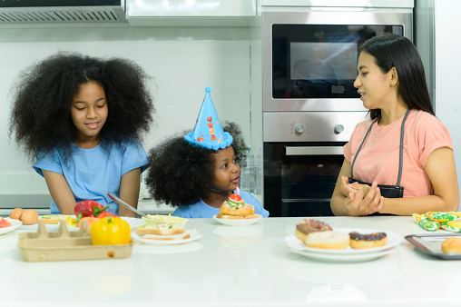 Asian-African American family Organize a birthday party for little sister in the kitchen of the house.