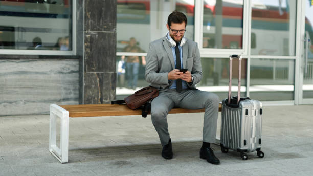 istock Businessman using phone while waiting for a train at train station 1403976338
