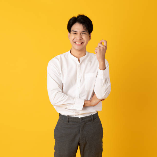 Good looking teenage asian man with laugh isolate on yellow background stock photo