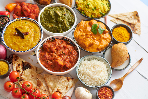 Assorted Indian various food with spices, rice and fresh vegetables on white wooden table. Flat lay. Top view.