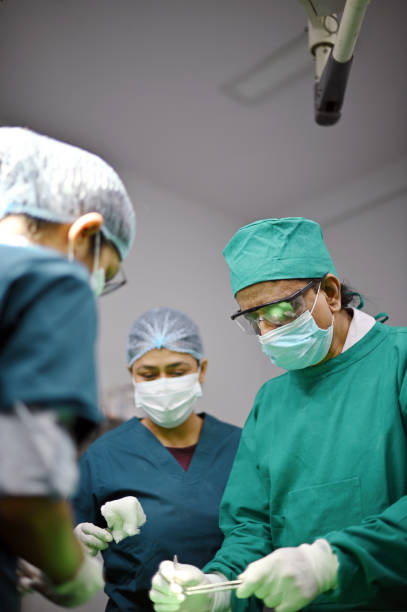 istock Senior Surgeon operating in a operating room while the assistant doctors/ Nurse assisting him 1403977935