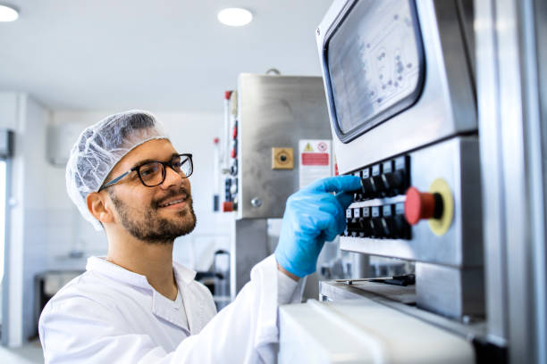 Pharmaceutical worker or technologist operating industrial machine for medicine production. stock photo