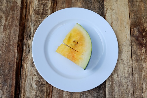 Fresh watermelon slices on white plate on wooden background