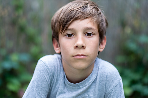 Portrait of a serious boy looking at camera while standing outdoors