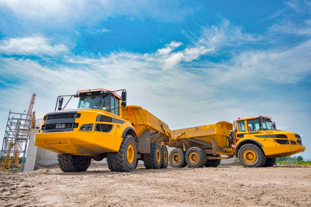 two yellow dump trucks parked side by side