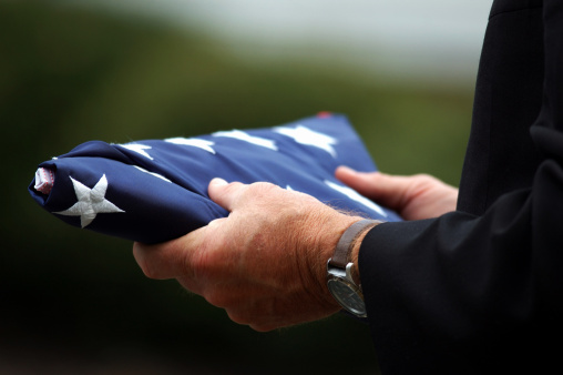 Close-up of a man's hands holding a folded American flag
