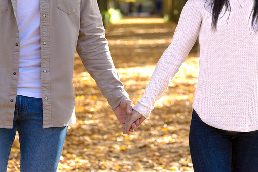 unrecognizable young couple strolling hand in hand in autumn