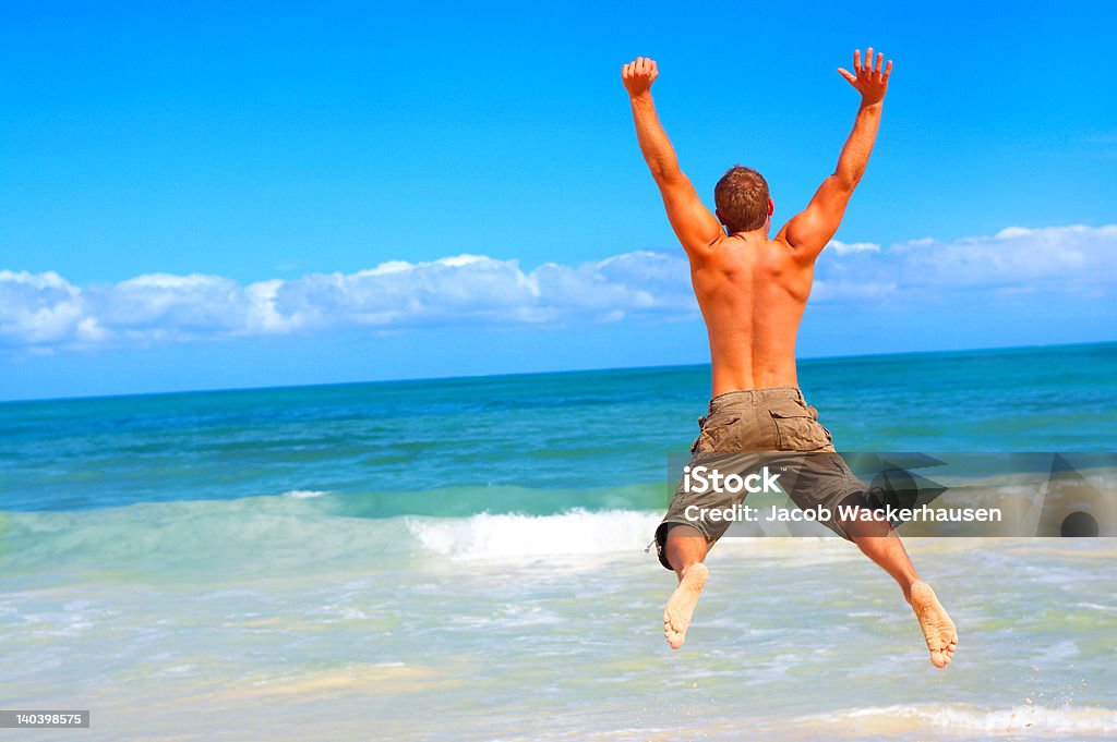 Salto de hombre en la playa - Foto de stock de Hombres libre de derechos