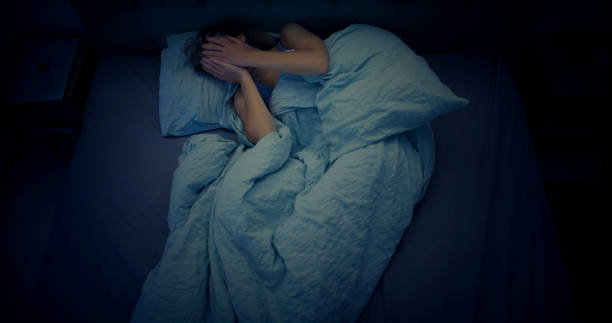 Woman in bed can't sleep due to insomnia stock photo