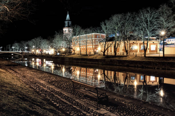The atmospheric Aura River in Turku, Finland flows peacefully at night in early spring. Turku Cathedral, built in the Middle Ages, can be seen illuminated in the background.