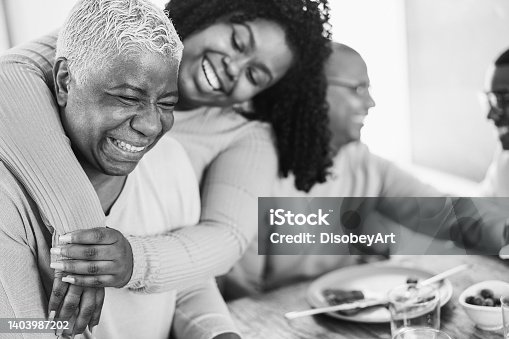 istock Happy african family eating lunch together at home - Focus on mother face - Black and white editing 1403987202