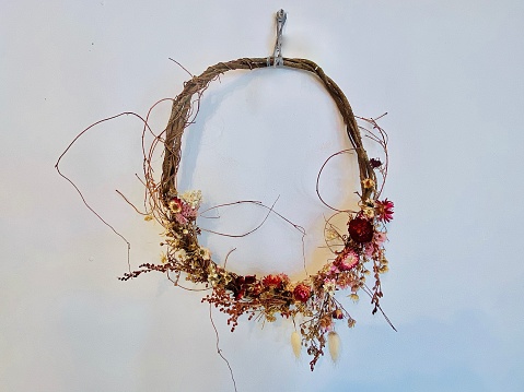 Horizontal still life of simple thin dried native Australian bush flowers decorative wreath display hanging on white wall