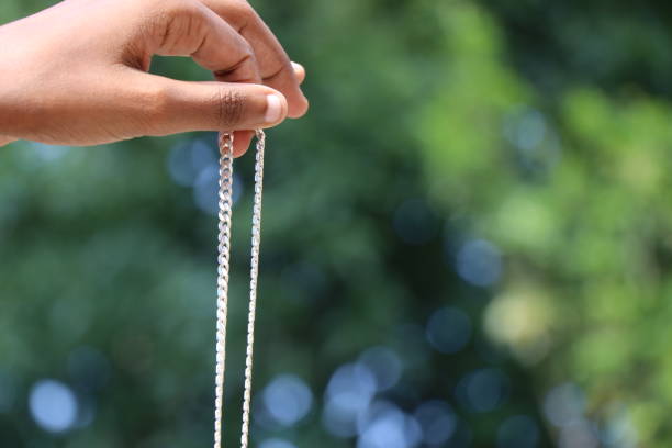 istock Holding a new silver chain in hand on green nature background 1403987536