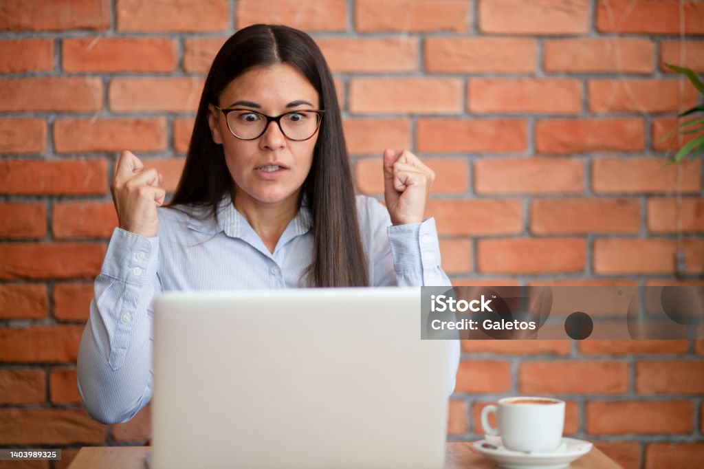 Ugh, I cannot believe this! Frustrated businesswoman feeling angry while reading a problematic e-mail on laptop in a café. Copy space. Adult Stock Photo