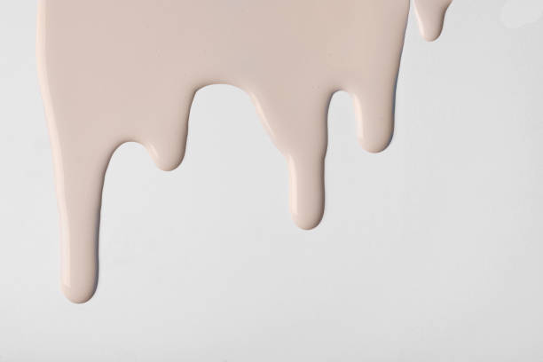 istock Light brown liquid drops of paint color flow down on isolated white background. Abstract beige backdrop 1403990764