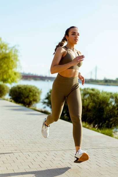 istock Young woman taking running exercise by the river promenade 1403991000